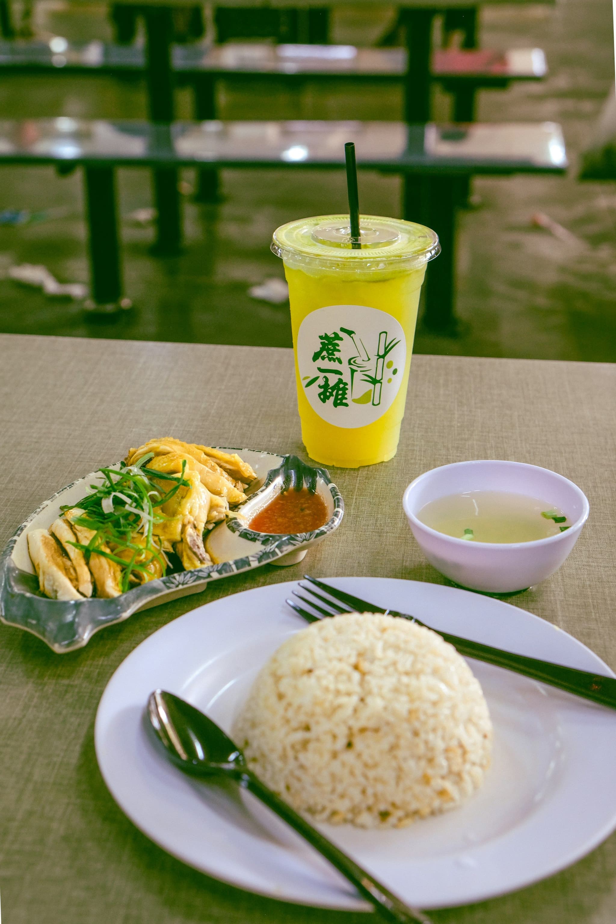 A plate of Hainanese chicken rice with a cup of sugarcane juice