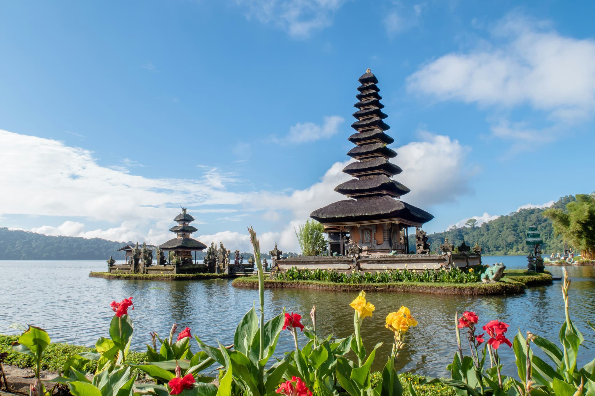 Temple in the middle of a lake surrounded by flowers and blue sky