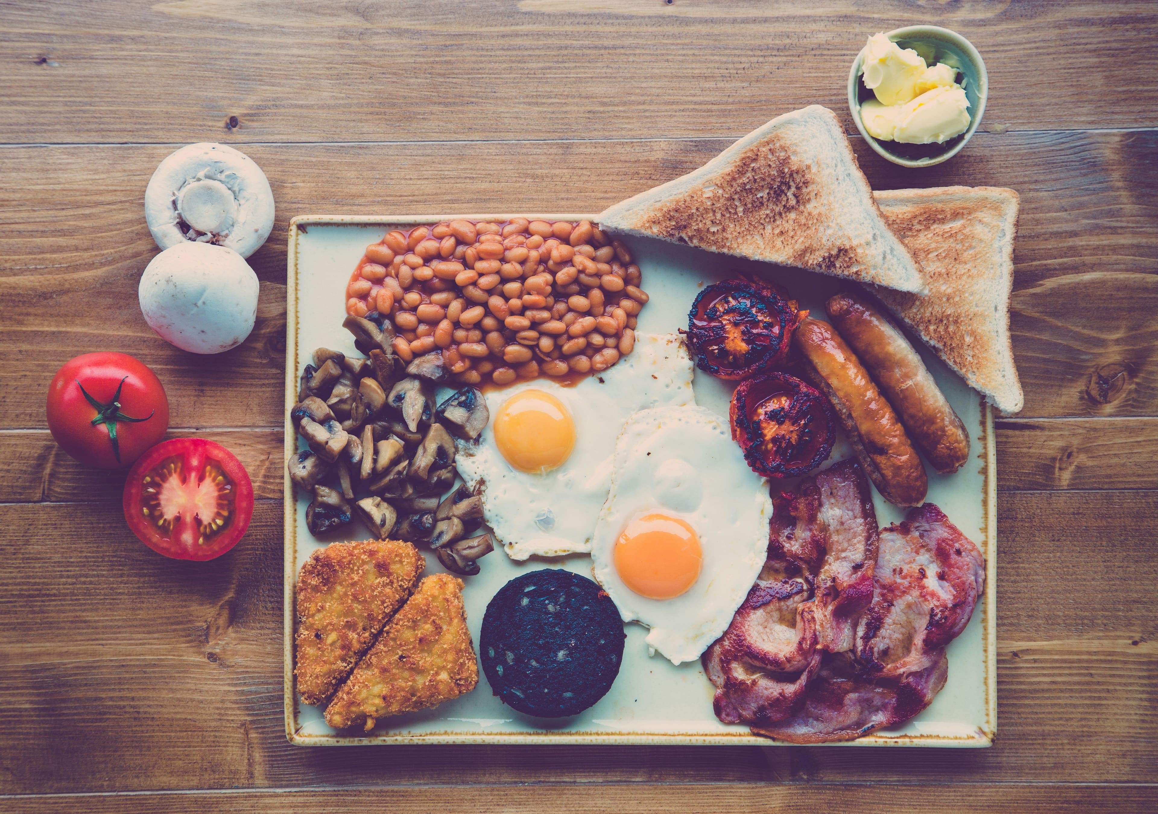 English breakfast with eggs, beans, bacon and toast on a tray on a wooden table