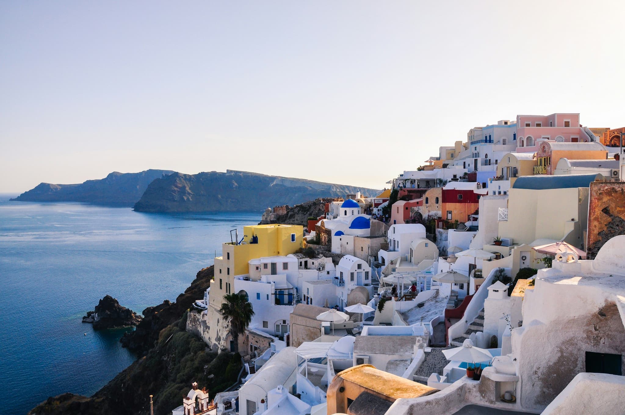 Coastal white and yellow houses on a hill in Santorini next to the beach