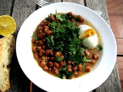 Ful medames dish with a hard boiled egg on a white plate