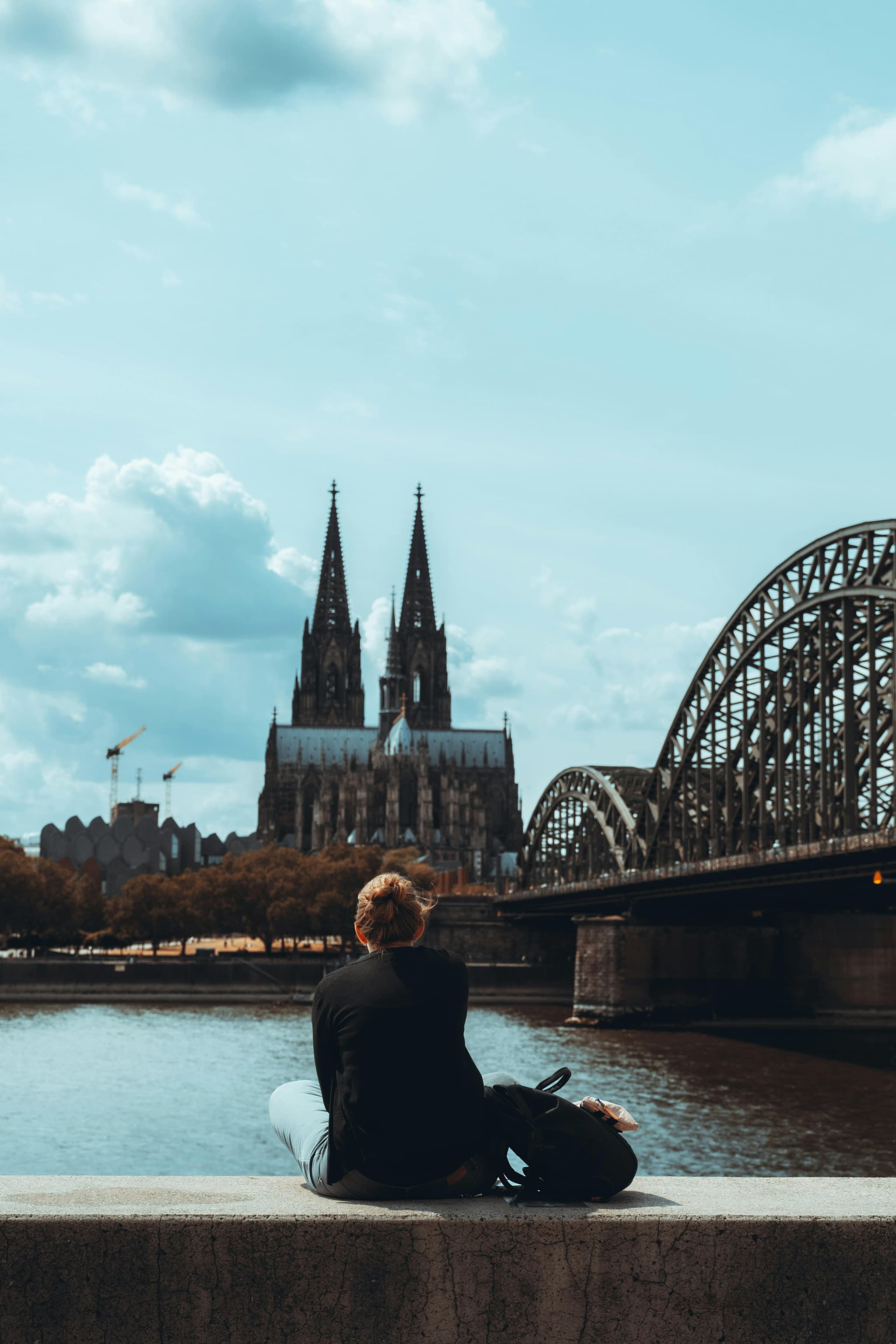 girl sitting next to a bridge