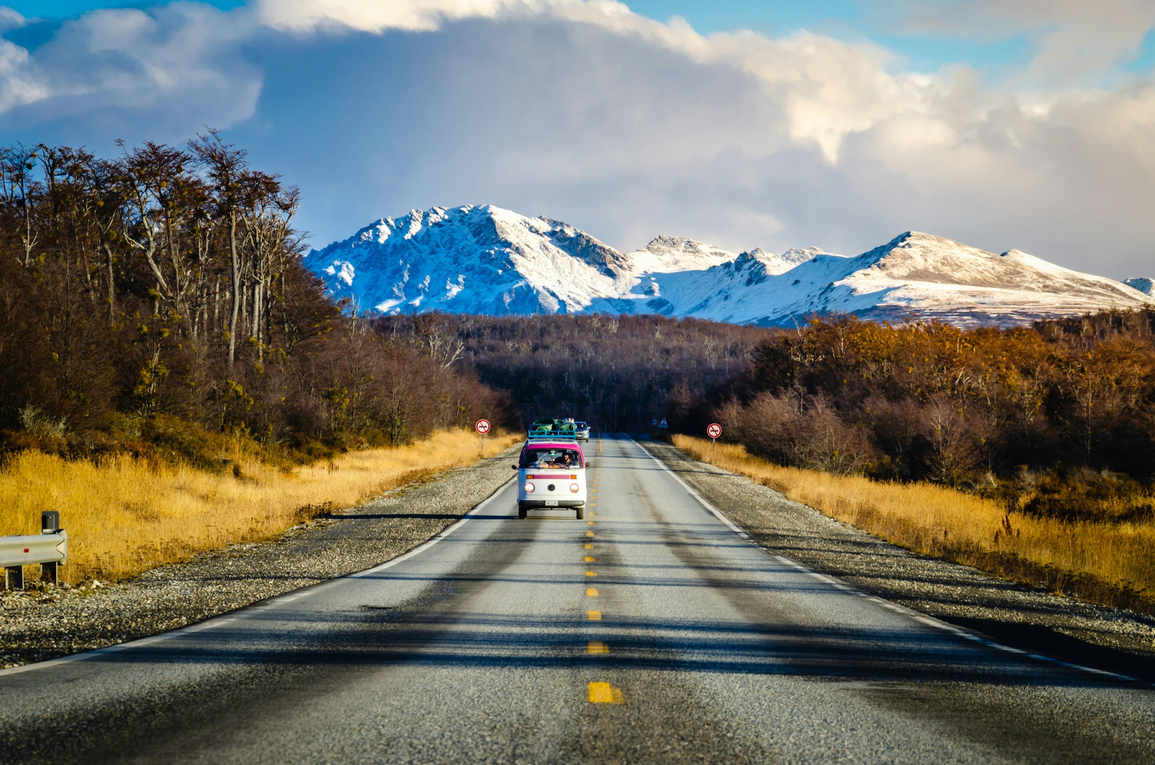 A campervan on a road in Tierra del Fuego with snow mountain in the background