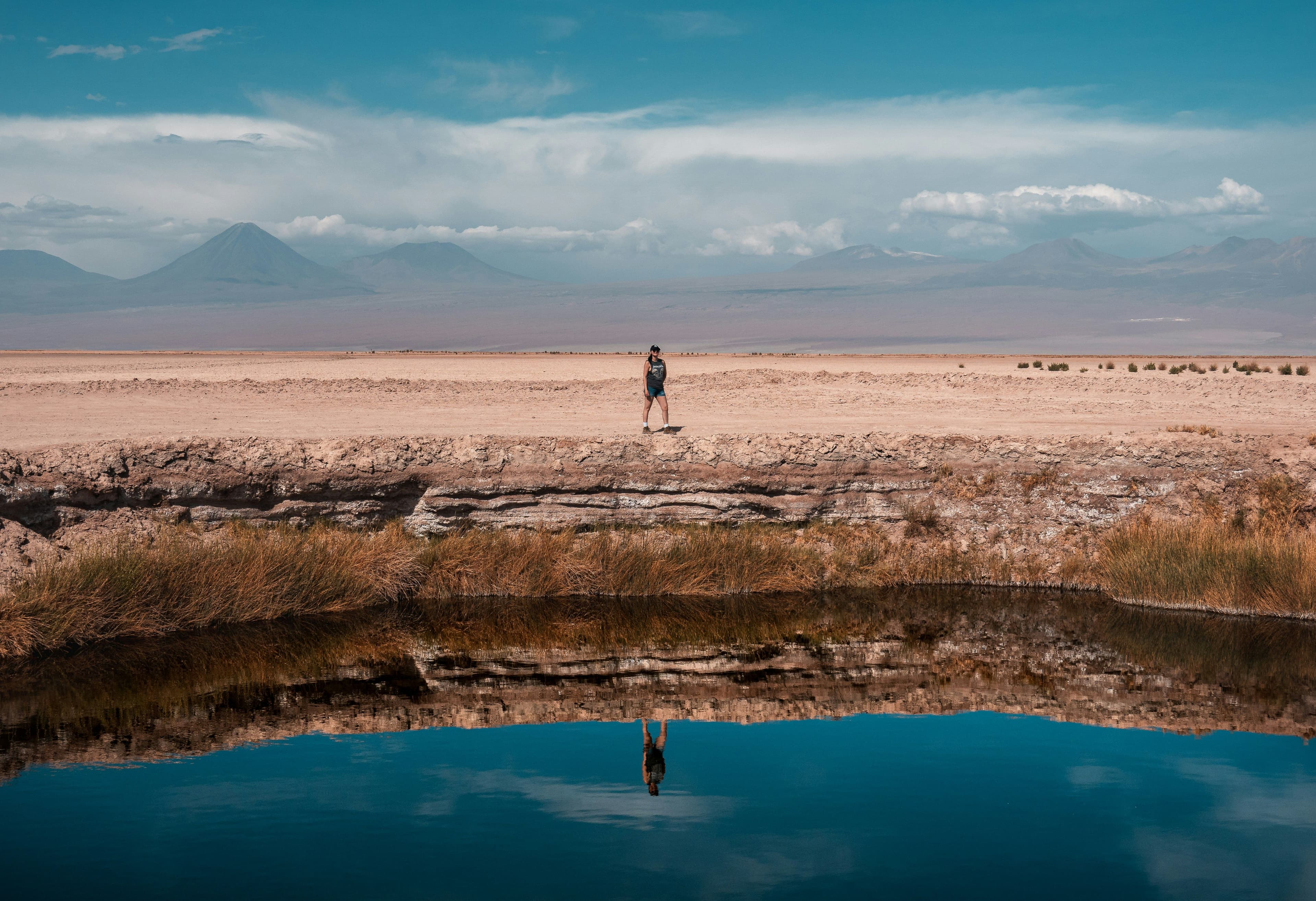 A man standing in front of a natural pool in San Pedro de Atacama in the dry landscape