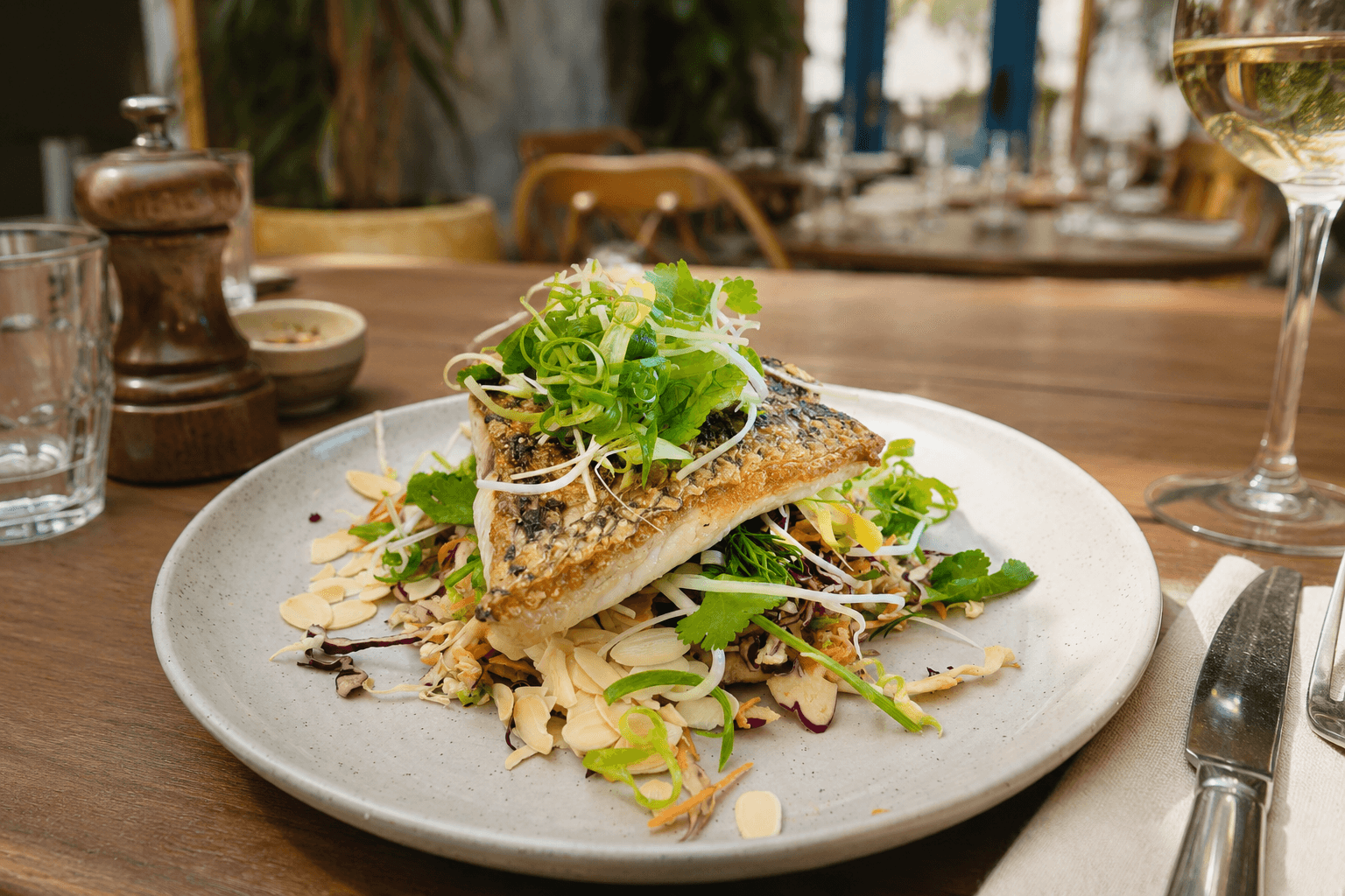 A plate with fresh fish filet and green vegetables in a restaurant.