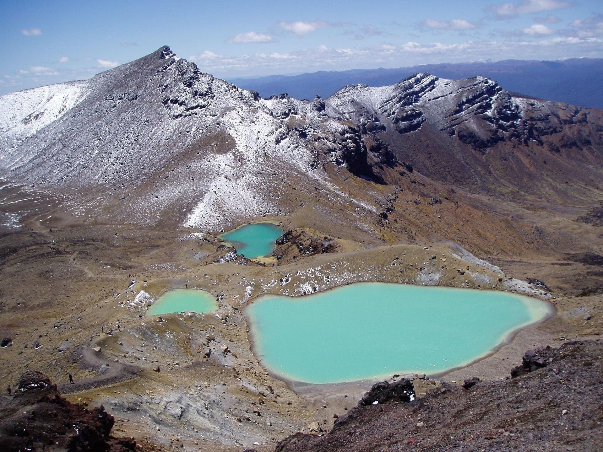 Tongariro Alpine Crossing Emerald Lake surrounded by rocky mountains with snow