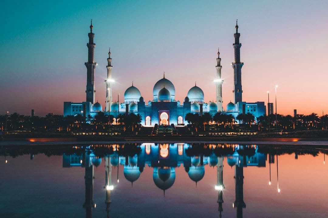 The Sheikh Zayed Grand Mosque reflected in its pool at low sun