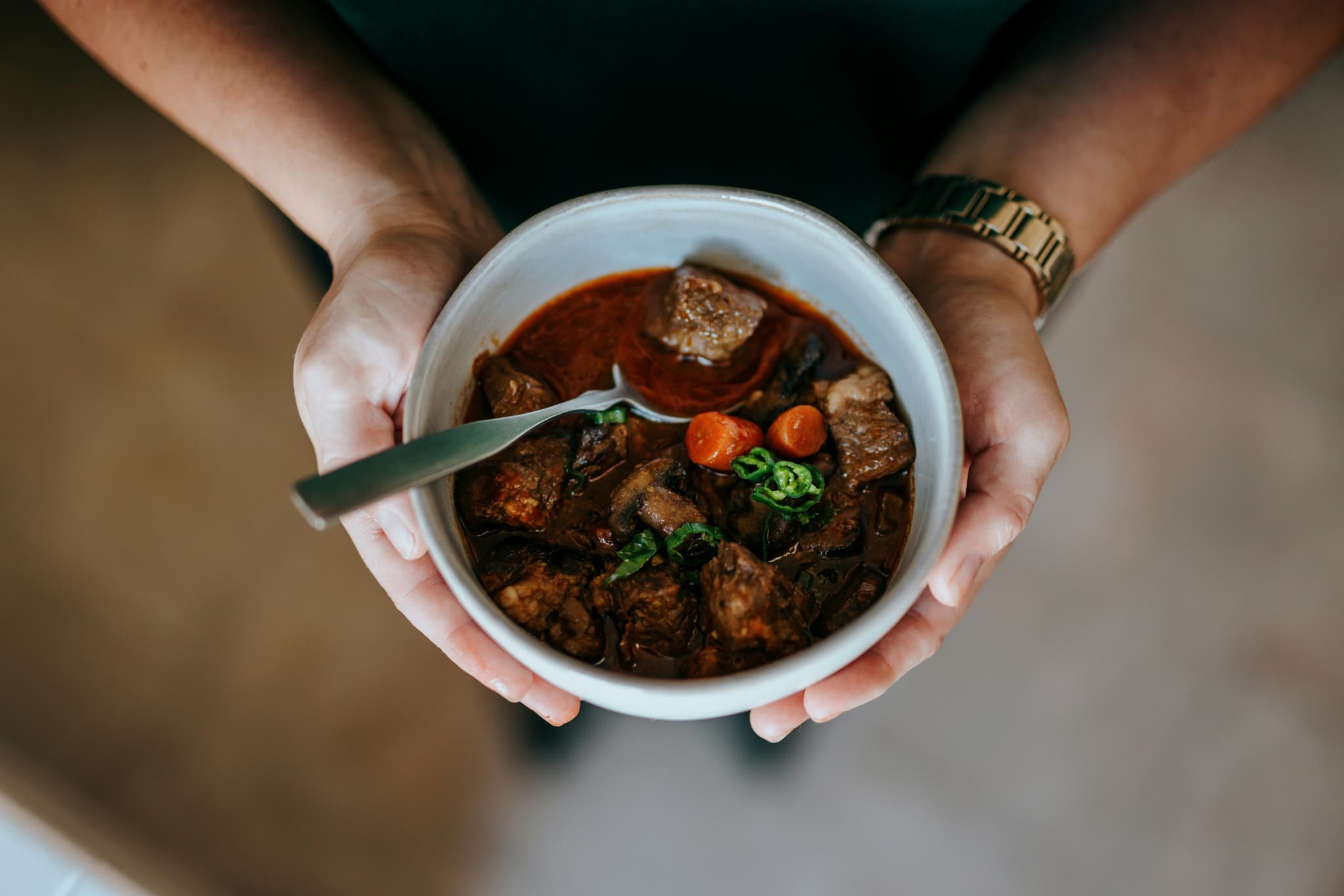 Woman hands holding bowl of Irish stew with meat
