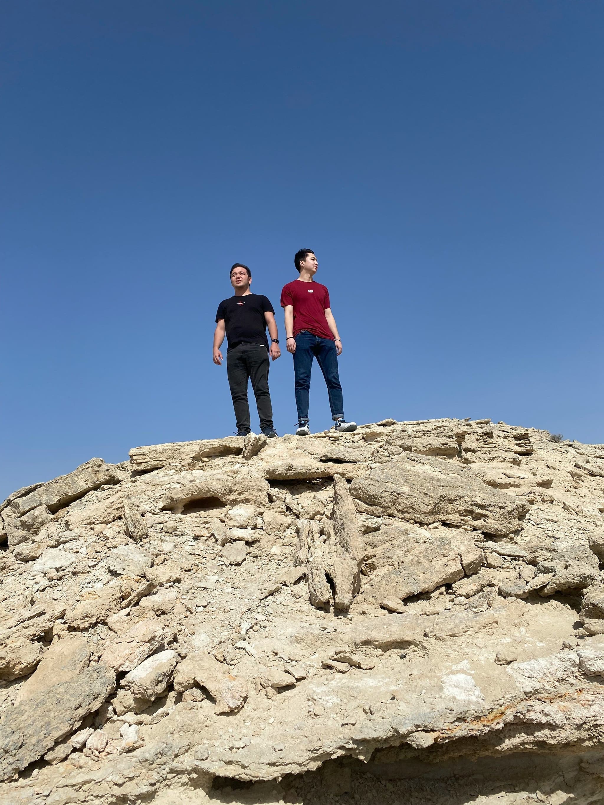 Two travellers standing on white chalk cliffs at Bozzhyra in Mangystau