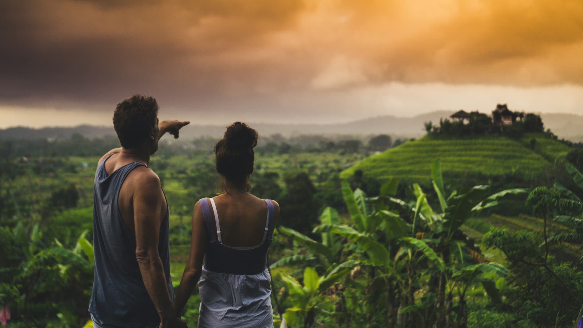 Two people standing in the rain forest rice field mountains in bali pointing at the valley