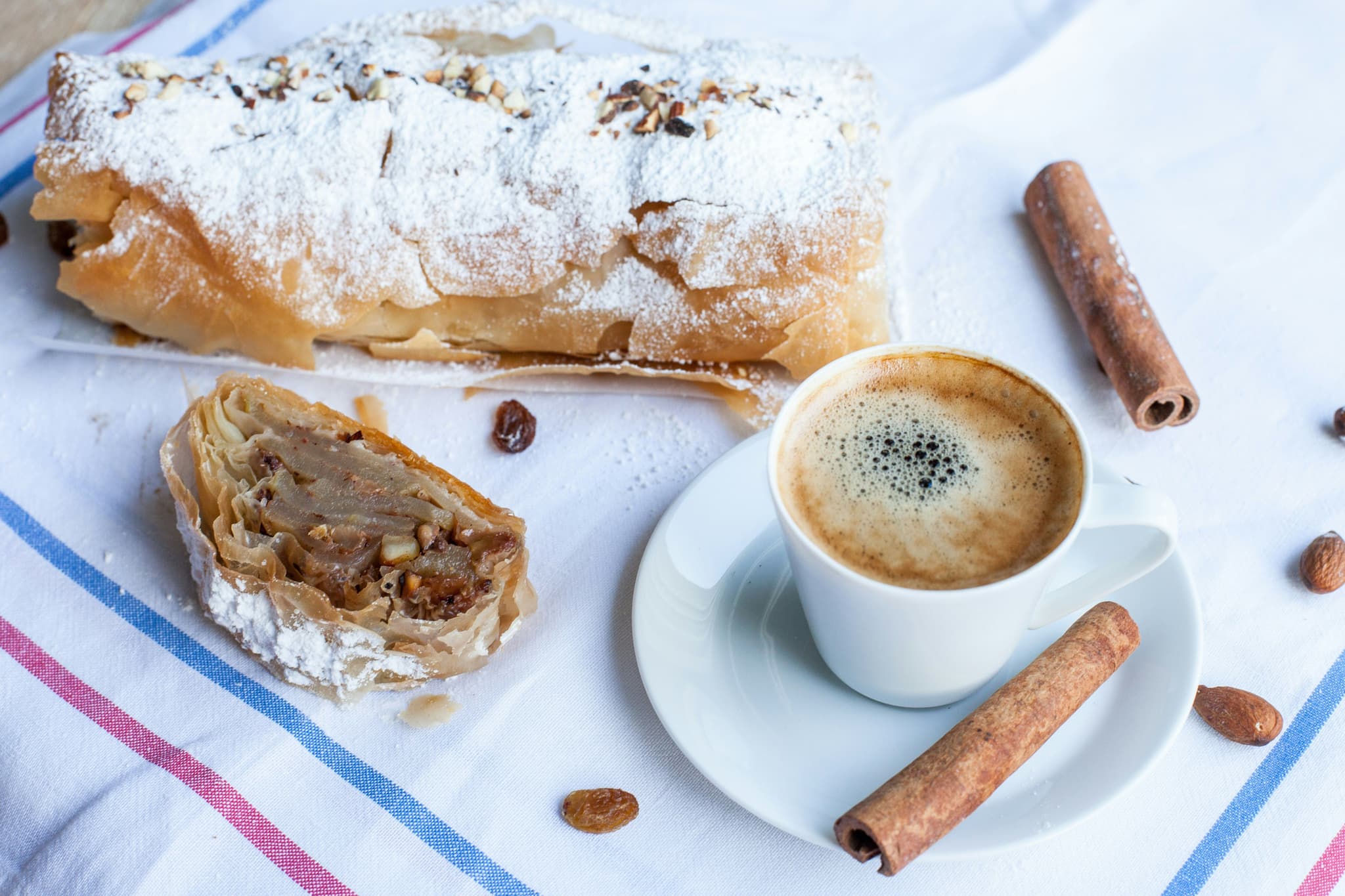 Apfelstrudel and coffee on a plate with cinnamon sticks