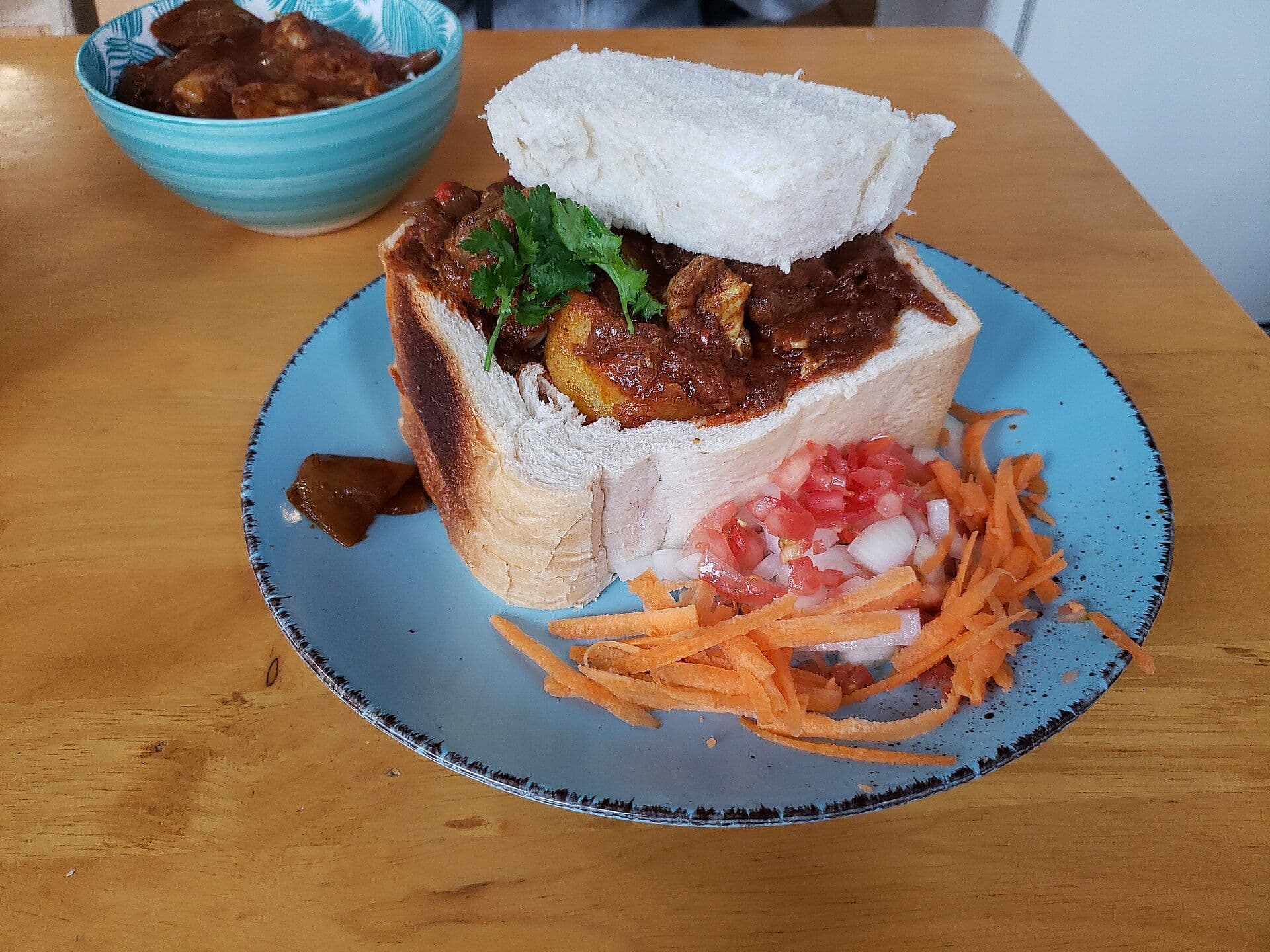 Bunny chow bread with meat inside and carrot strips on the side