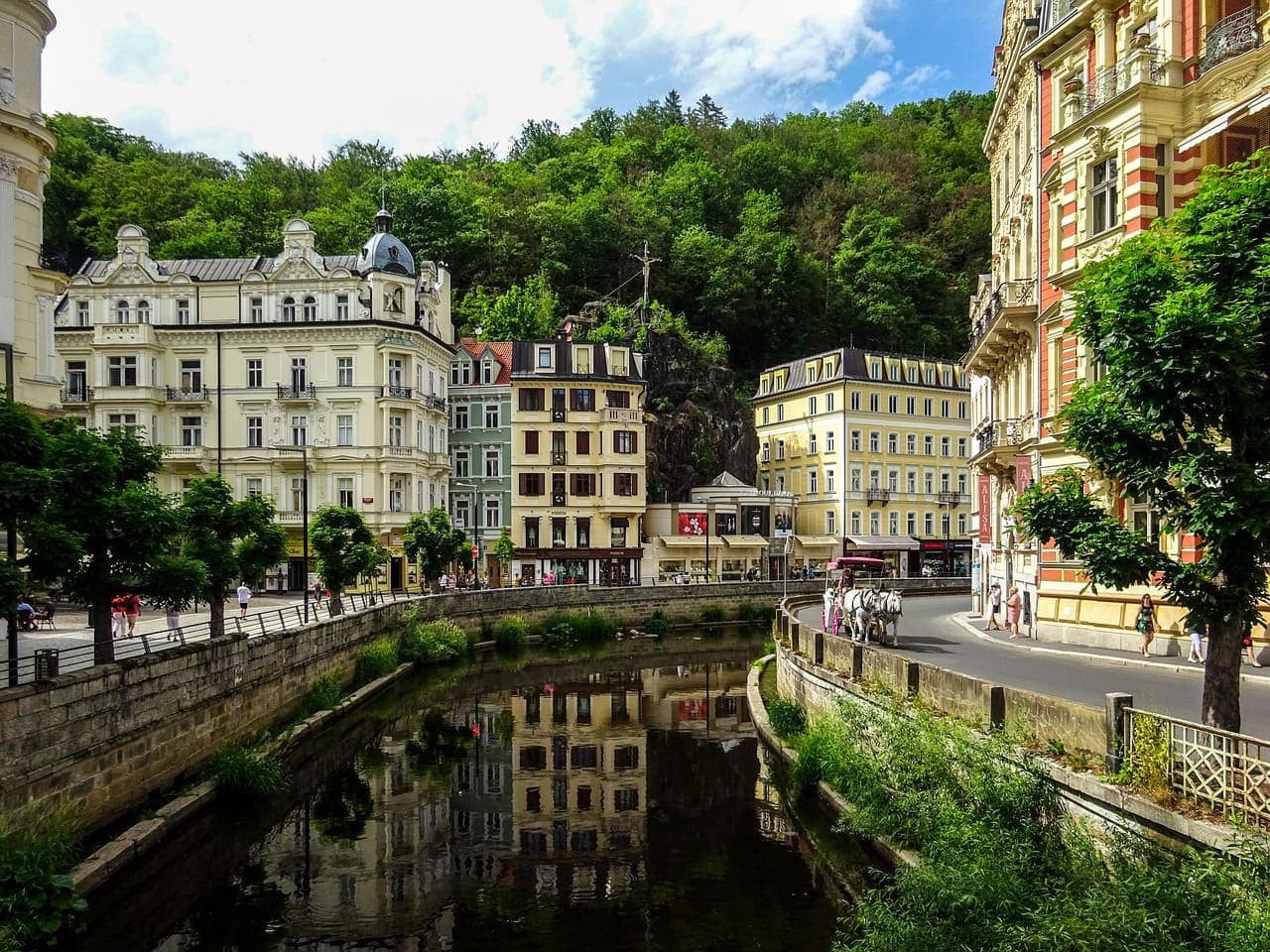 Canal and historic houses in Brno with pastel façades and greenery along the water in a quiet city street.