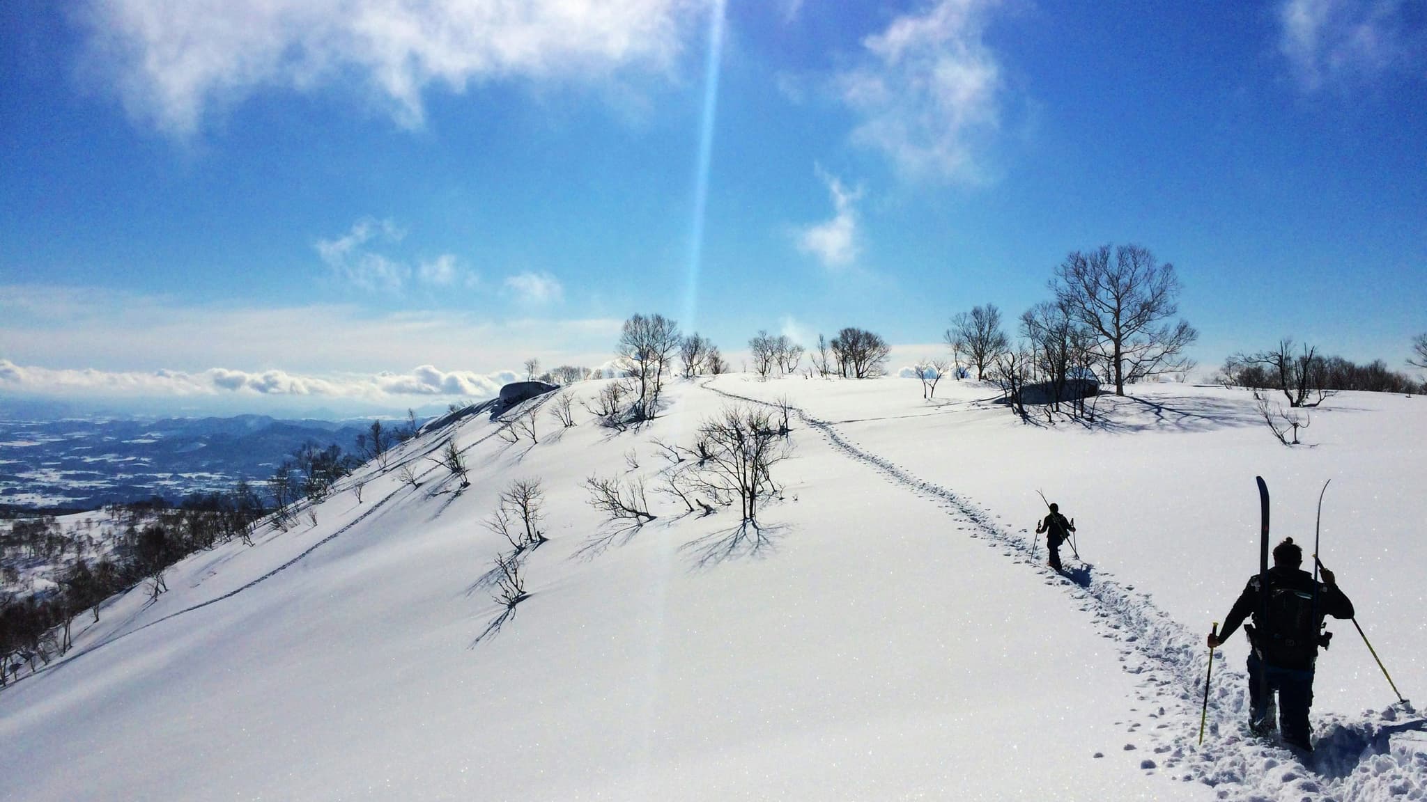 Snow covered mountain top with people skiiing on a clear day
