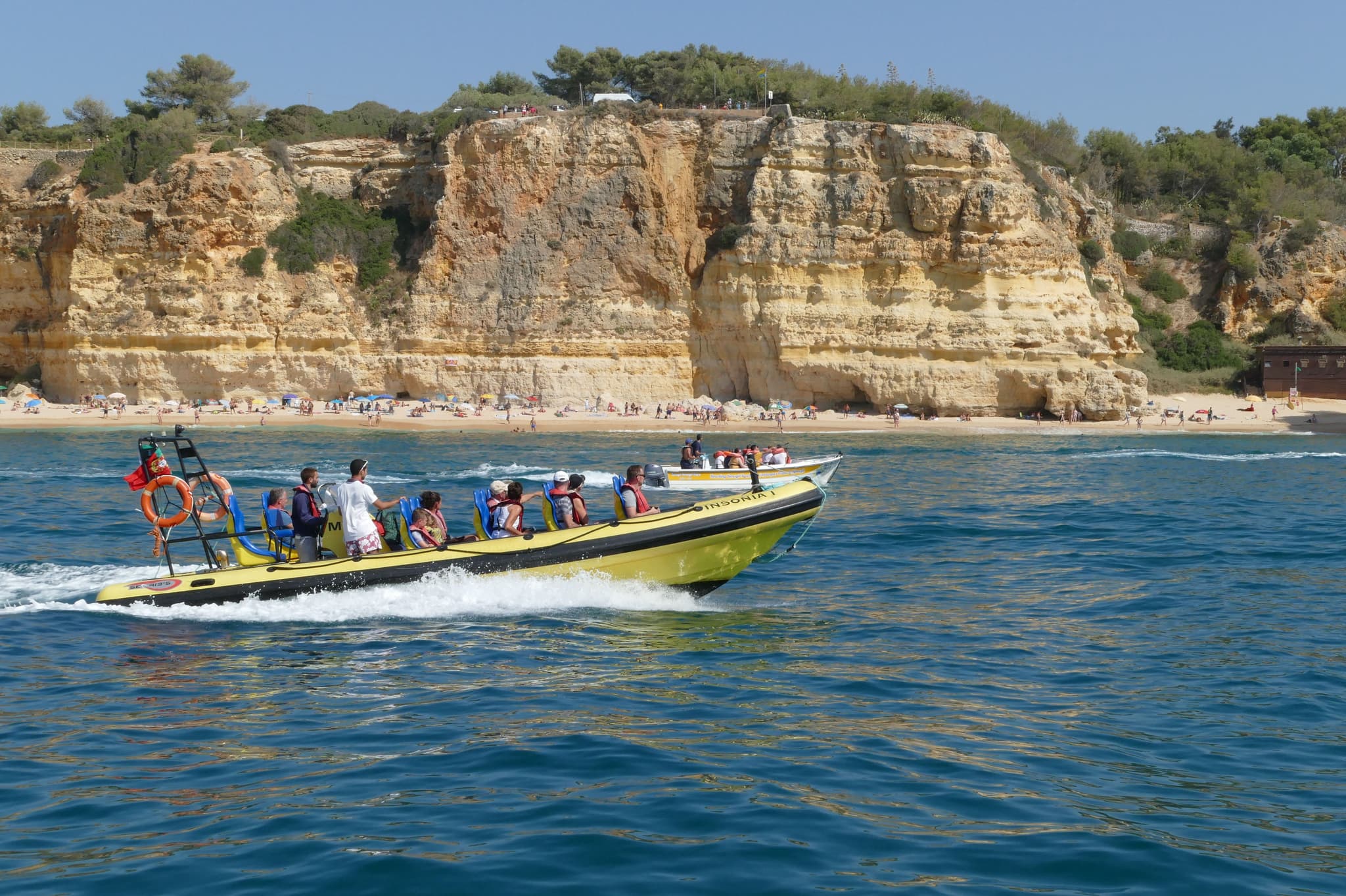 Side view of a boat on the water near a cliff in Algarve coast