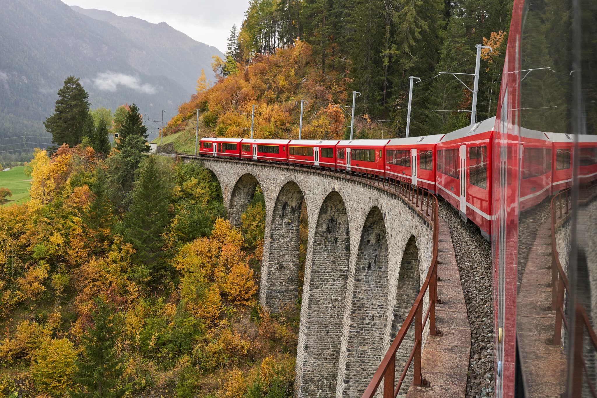 Glacier Express train crossing a stone viaduct in the Swiss Alps