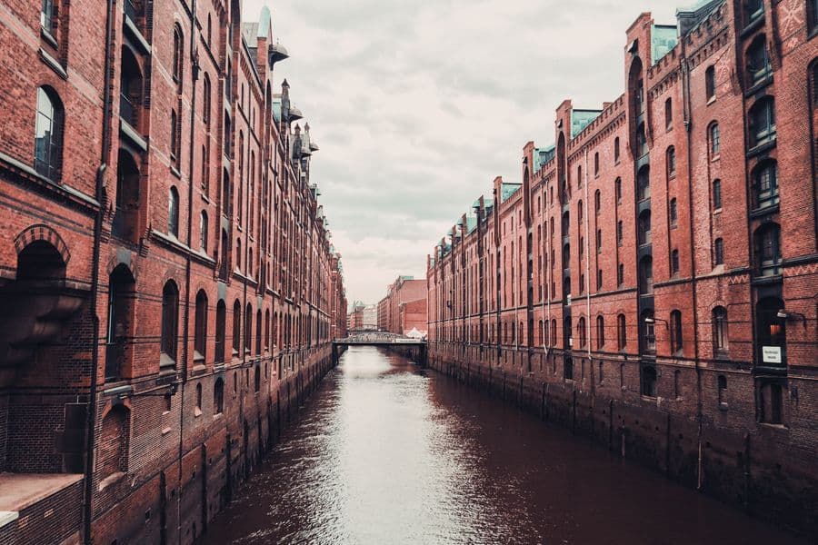A wide daytime shot of the historic red brick warehouses in Hamburg standing next to a water canal.