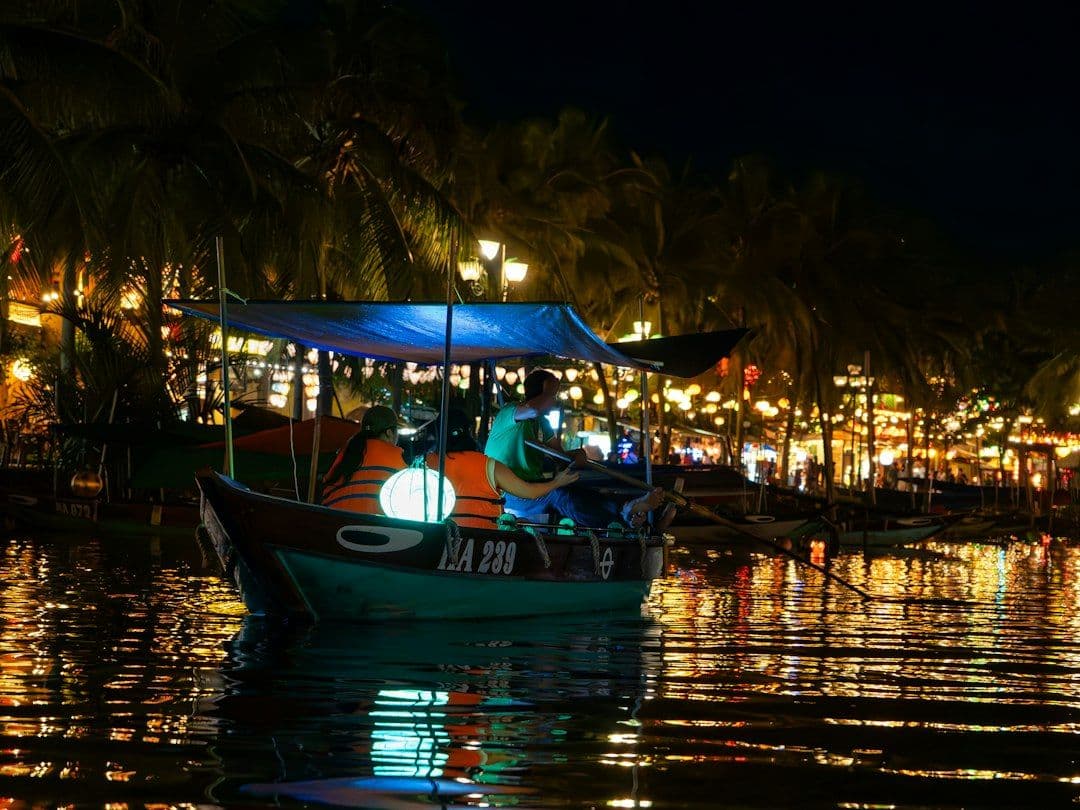 A traditional wooden boat with glowing lanterns on the Thu Bon River in Hoi An at night