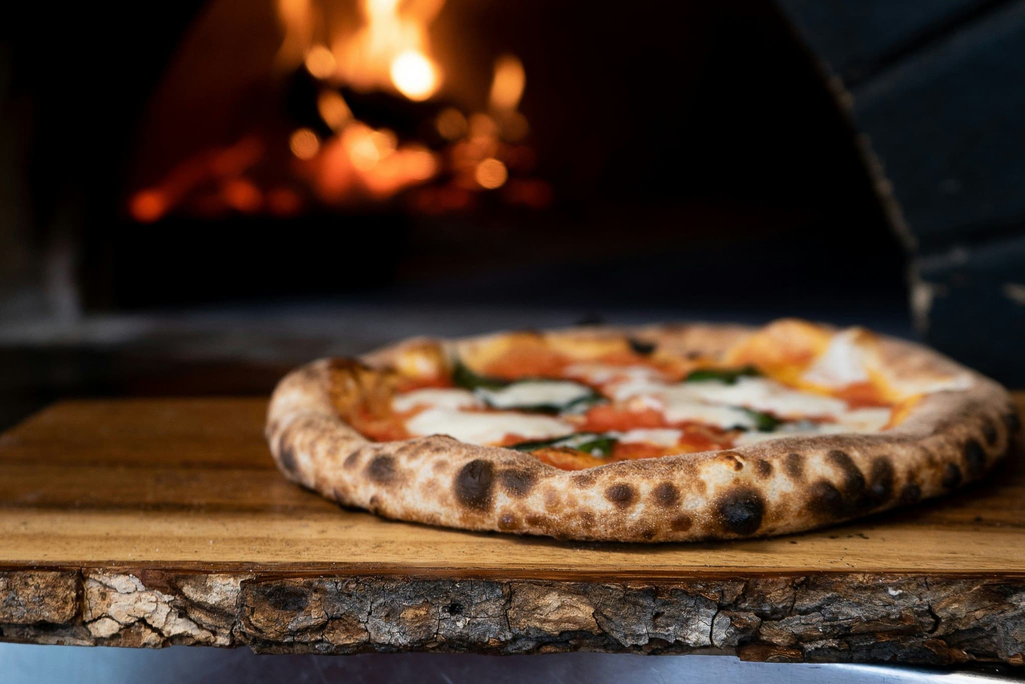 Fresh pizza in front of pizza oven