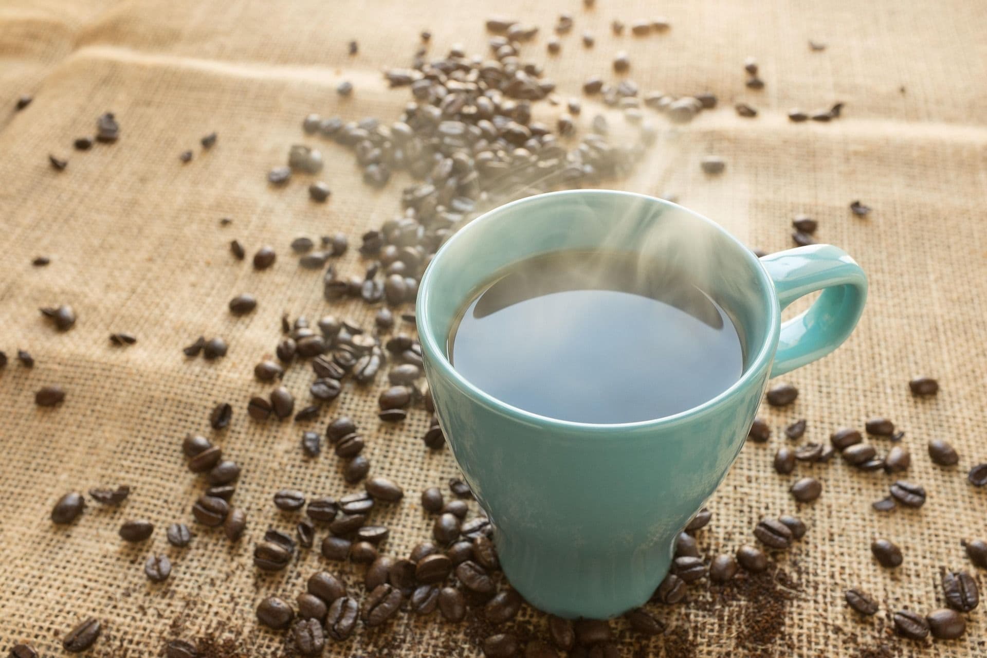 Cup of coffee surrounded by coffee beans