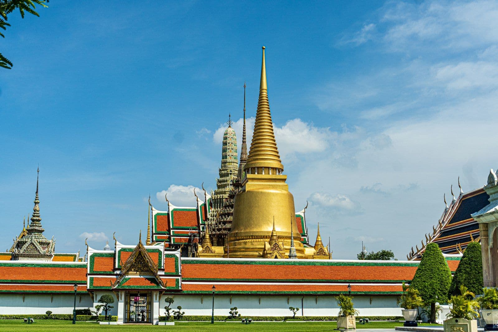 The Grand Palace in Bangkok, Thailand, with its gilded, ornate rooftops under a blue sky