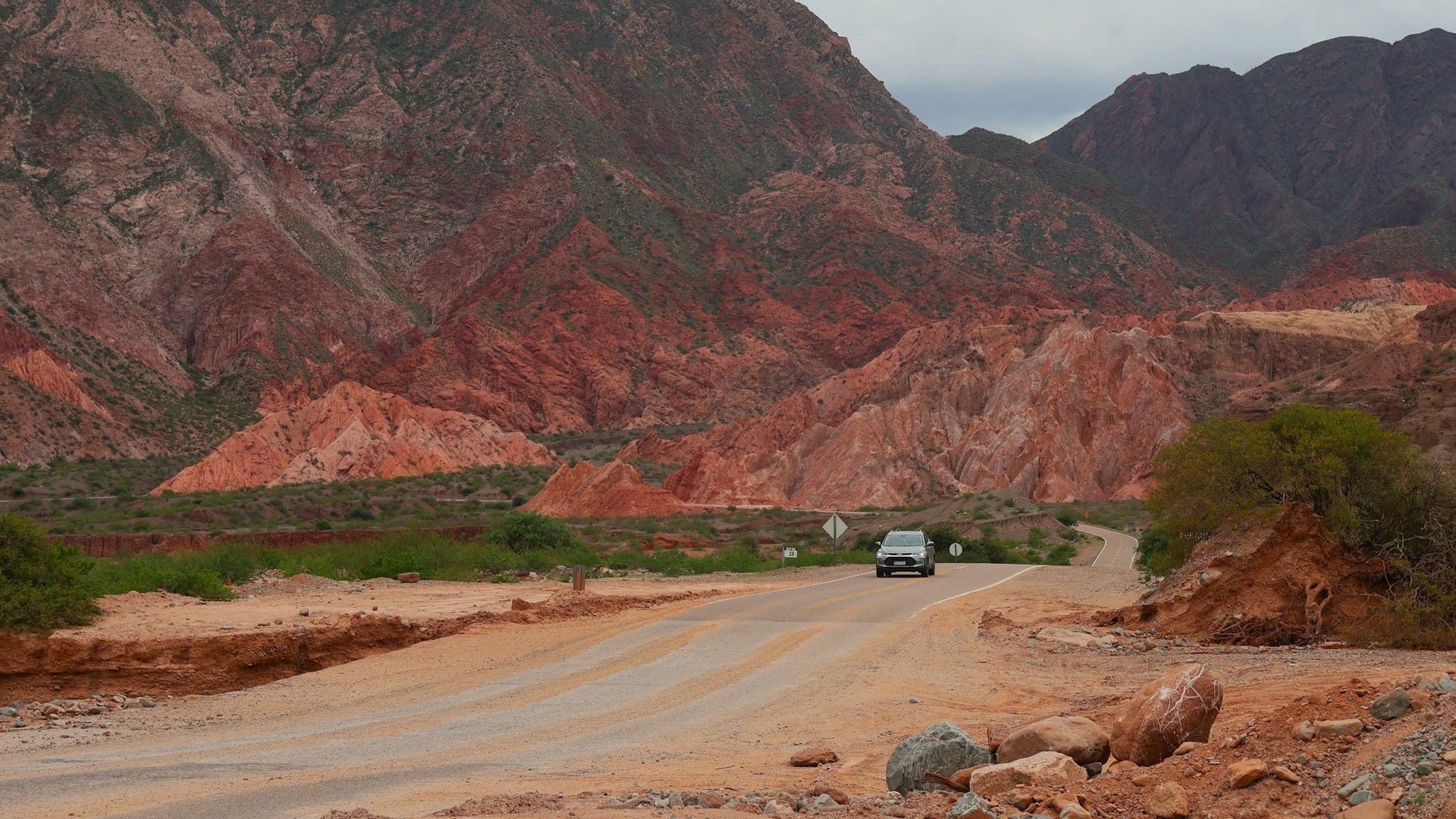 A car on a road winding through red rock mountains
