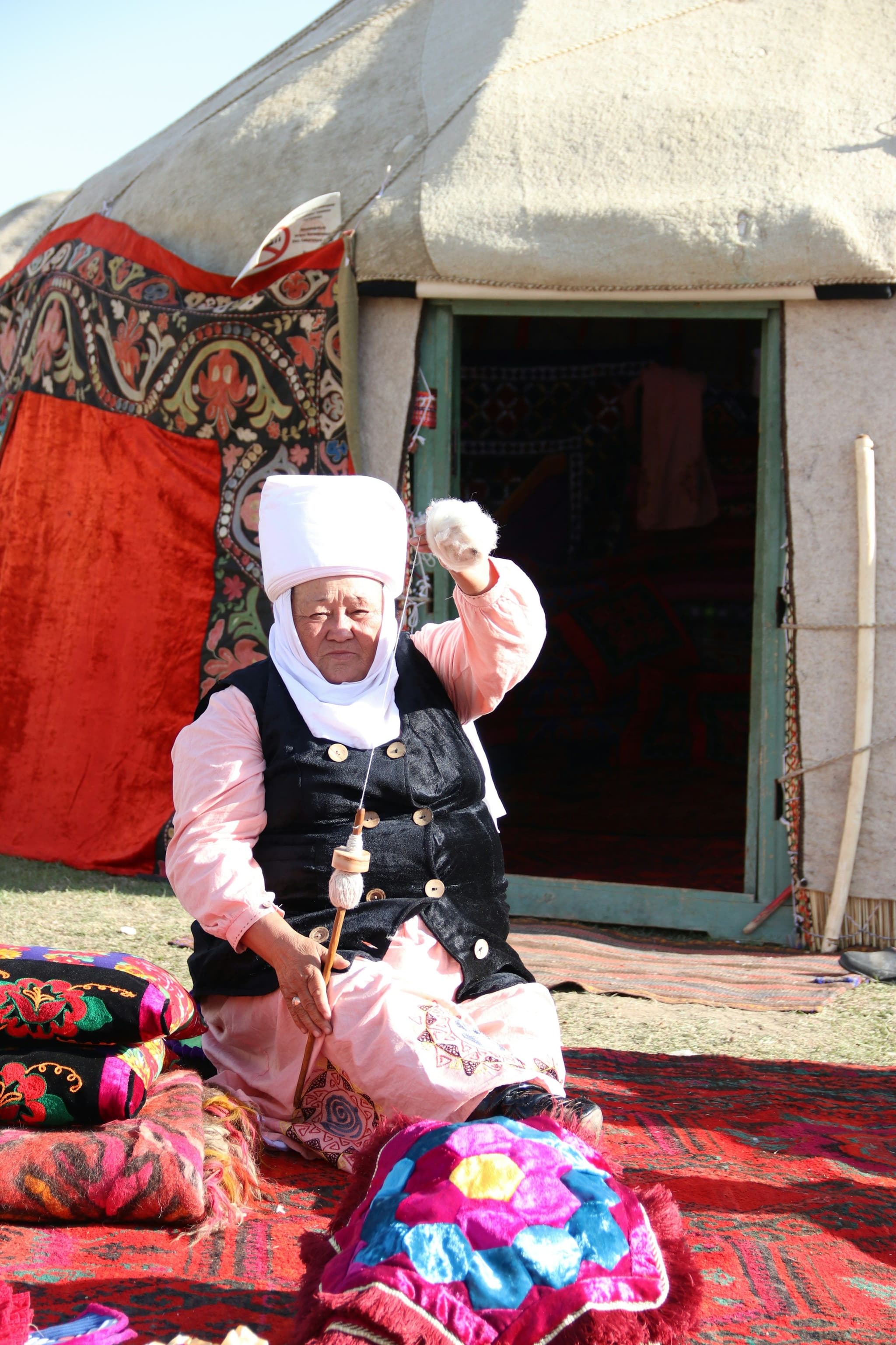 A woman seated outside a yurt at the World Nomad Games