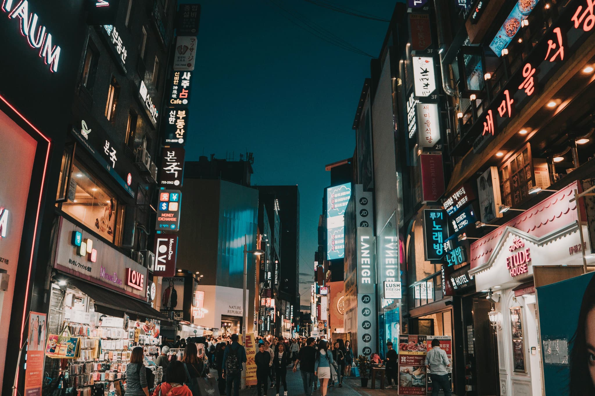 Street with billboards and neon signs of Seoul with people shopping at night