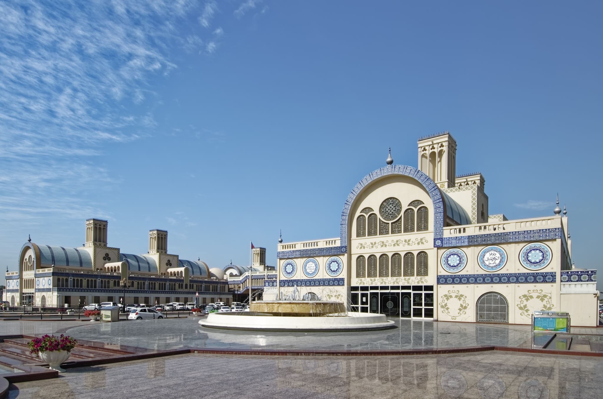 A mosque in Sharjah with a fountain on a sunny day