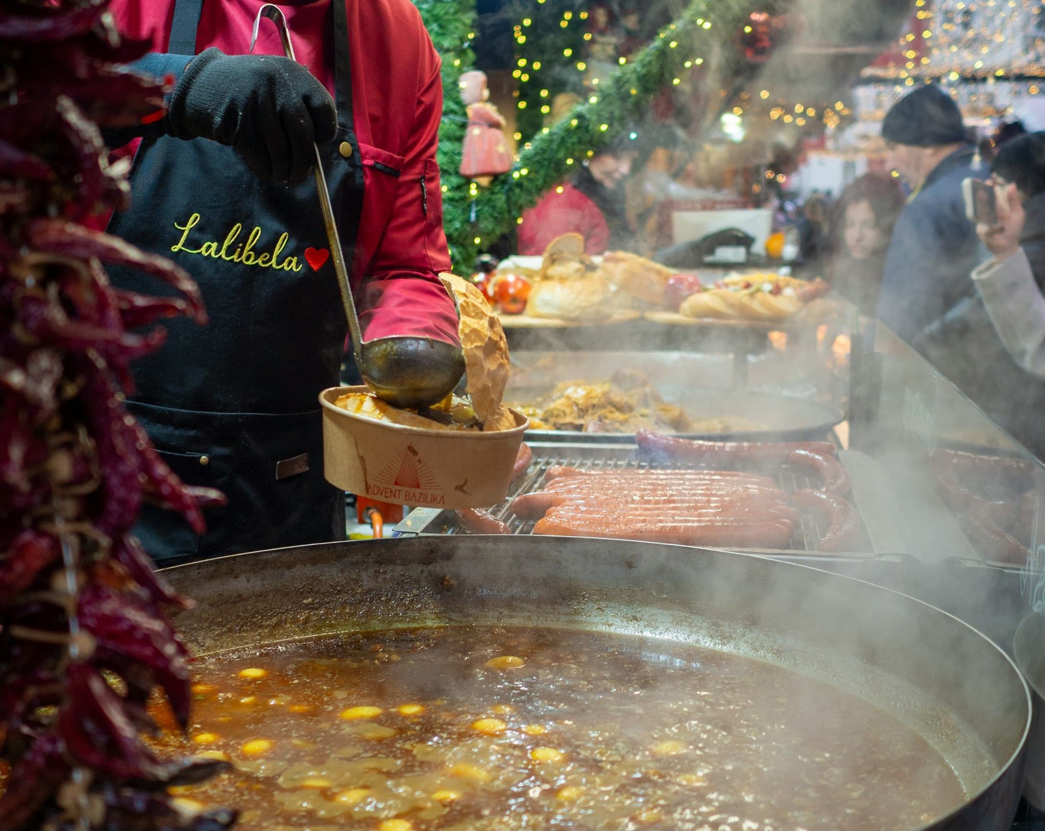 A vendor ladling a traditional Hungarian stew from a large pot at a Budapest Christmas market