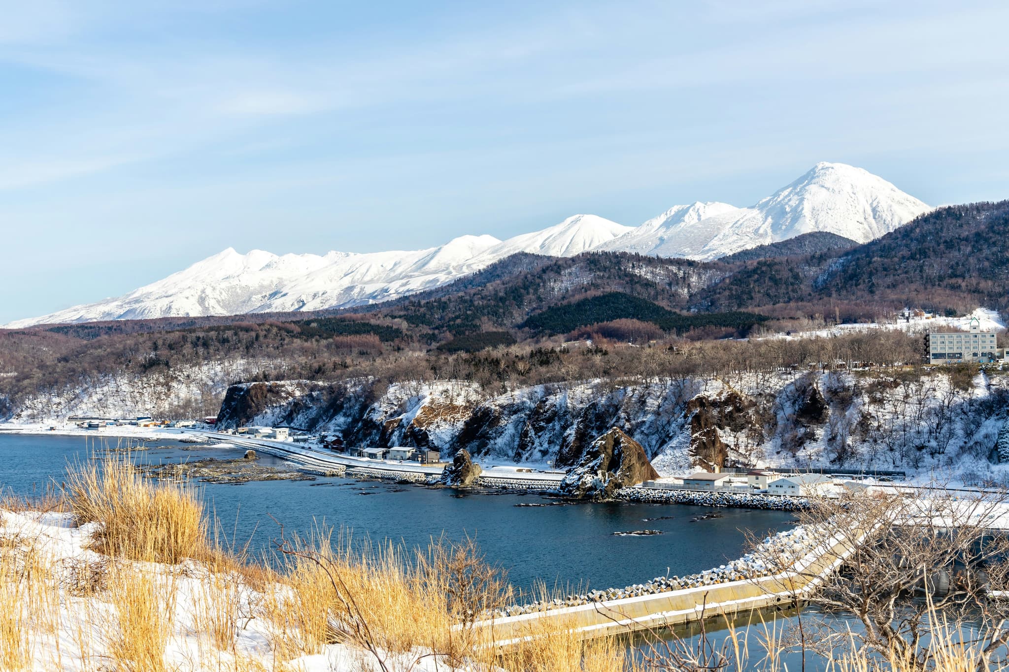 A mountain and grass land covered in snow in Hokkaido and a lake