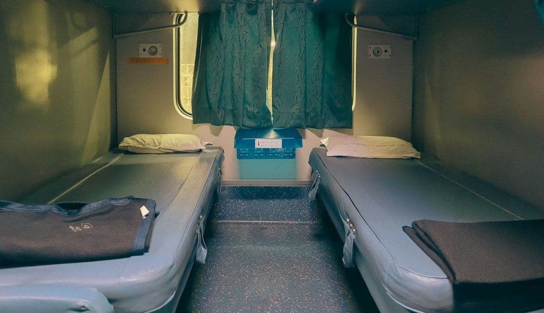 Two bunk beds inside a train sleeper cabin, similar to a European night-train couchette.