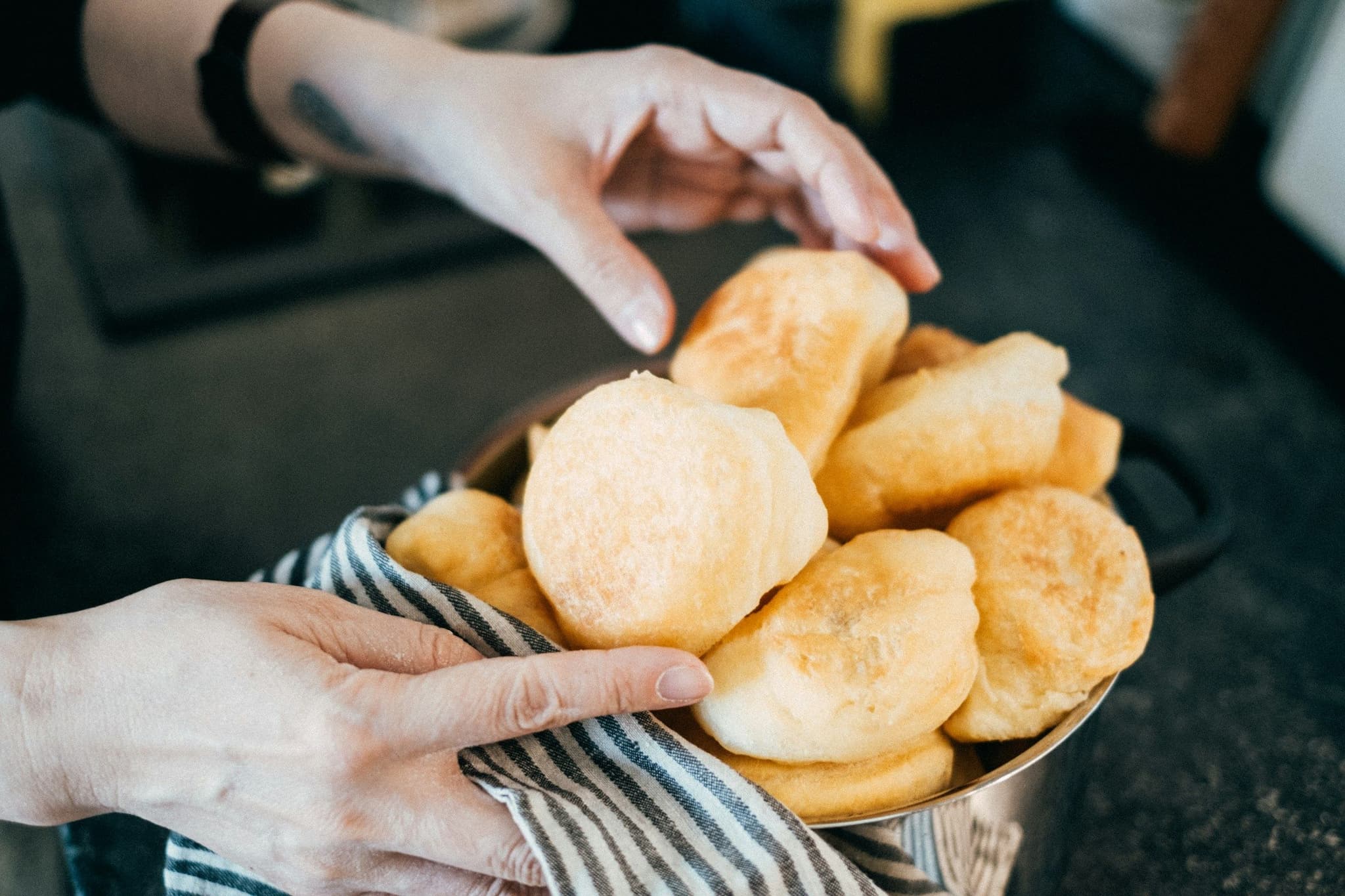 A hand reaching for fried dough in a bowl