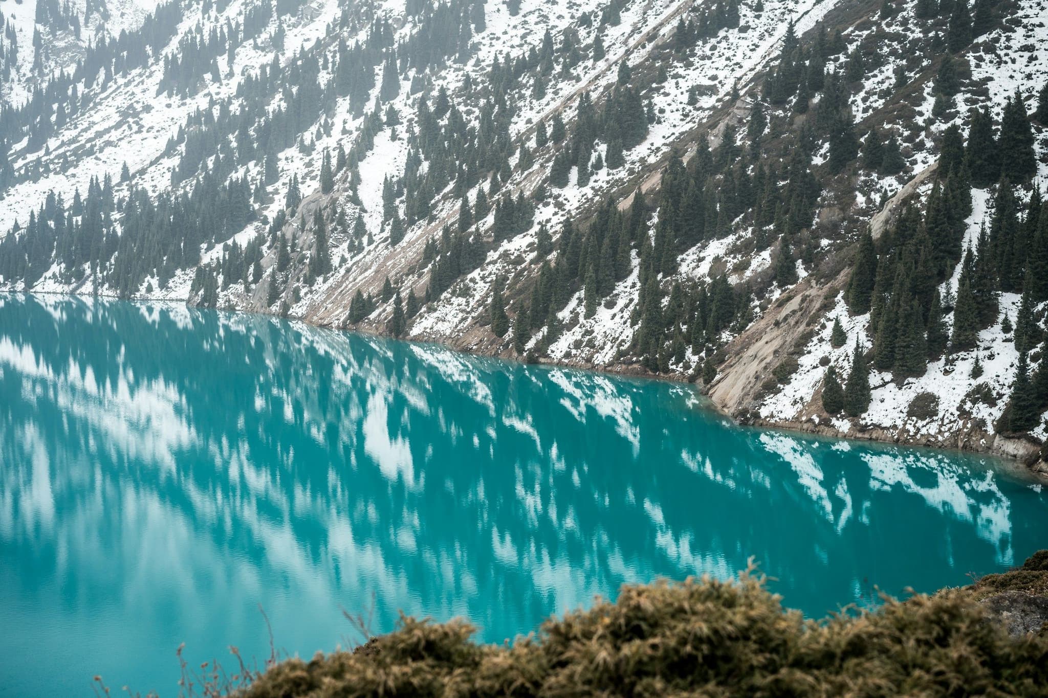 A calm mountain lake below steep peaks near Almaty