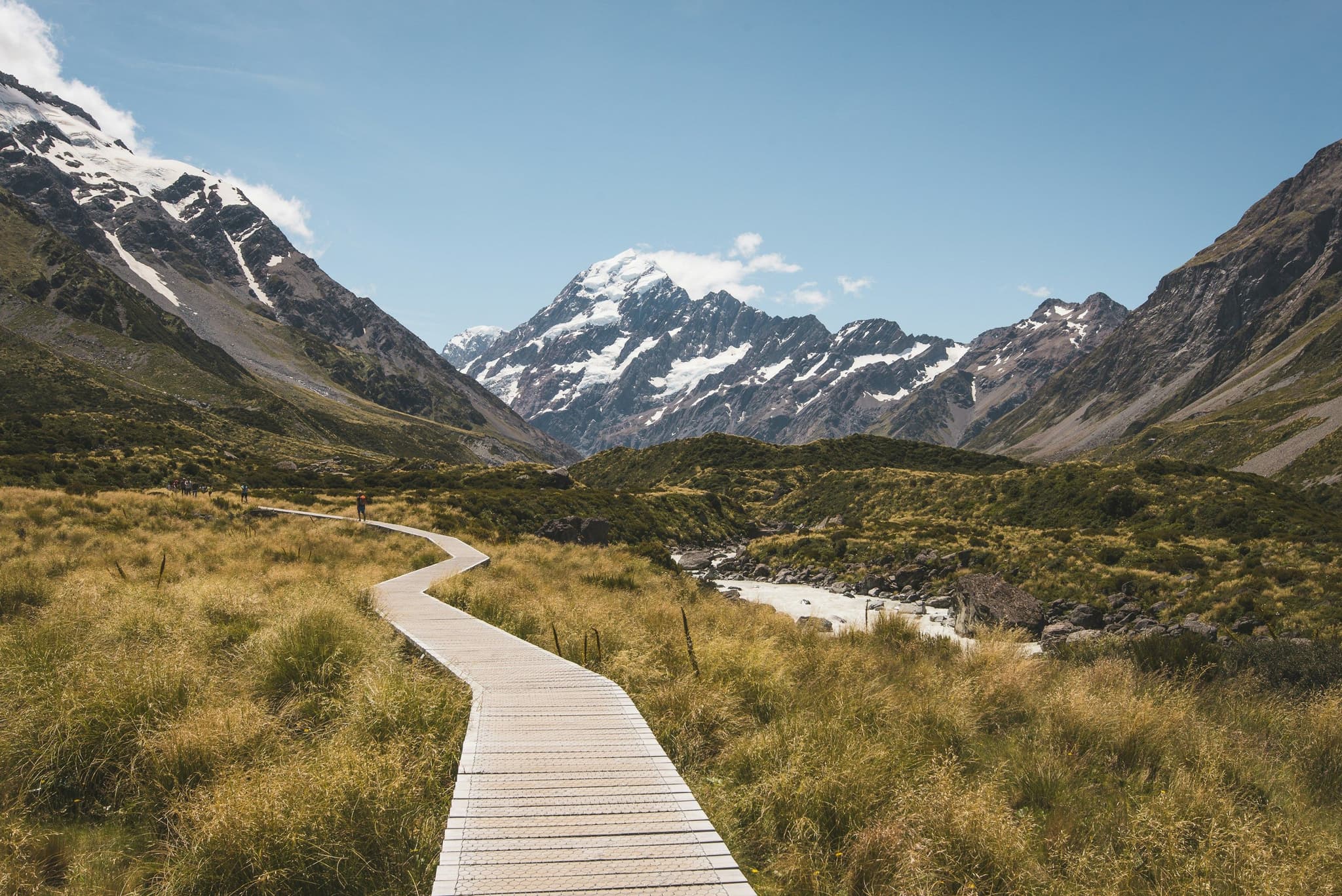 Walking track wooden between grass and mountains in Hooker Valley