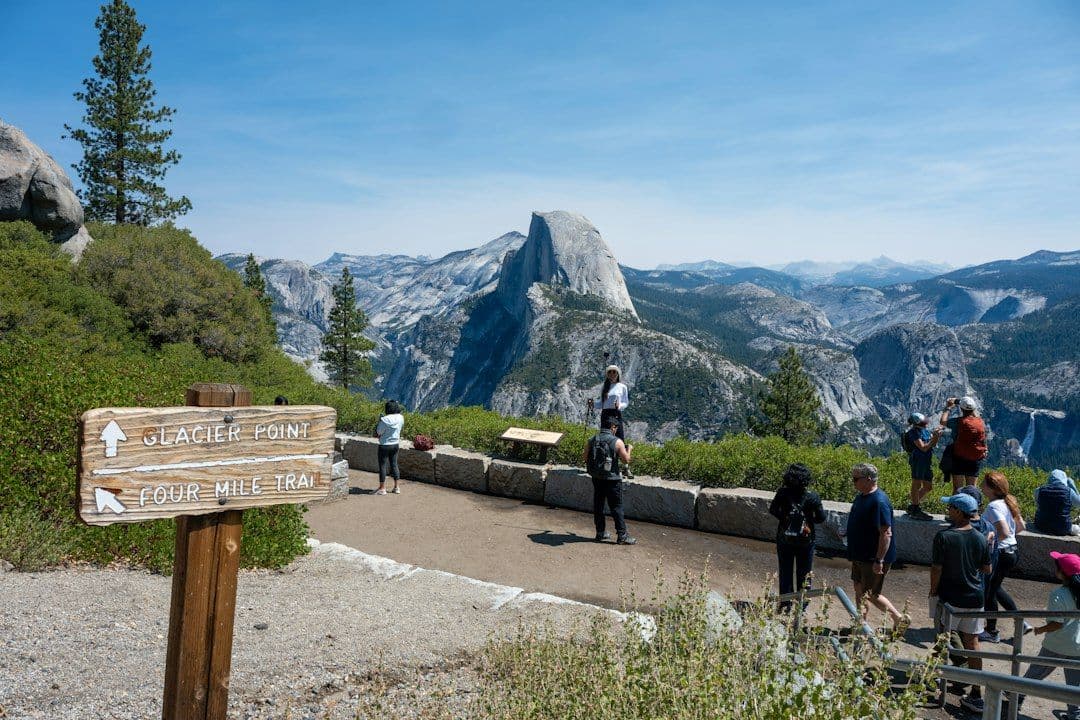 Visitors at a crowded viewpoint admiring Half Dome in Yosemite National Park.