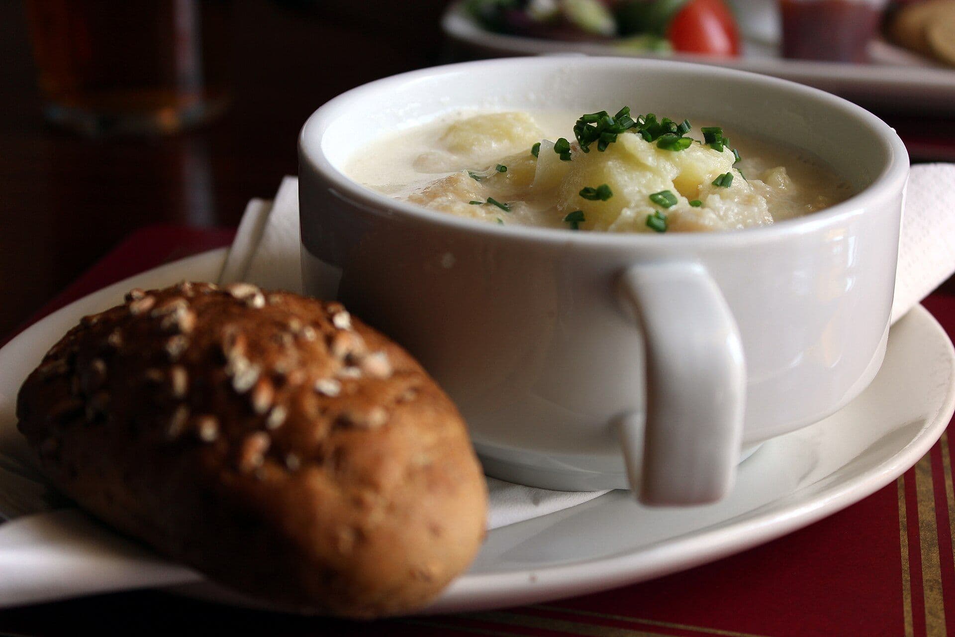Cup with soup called Cullen skink with a piece of brown baguette next to it
