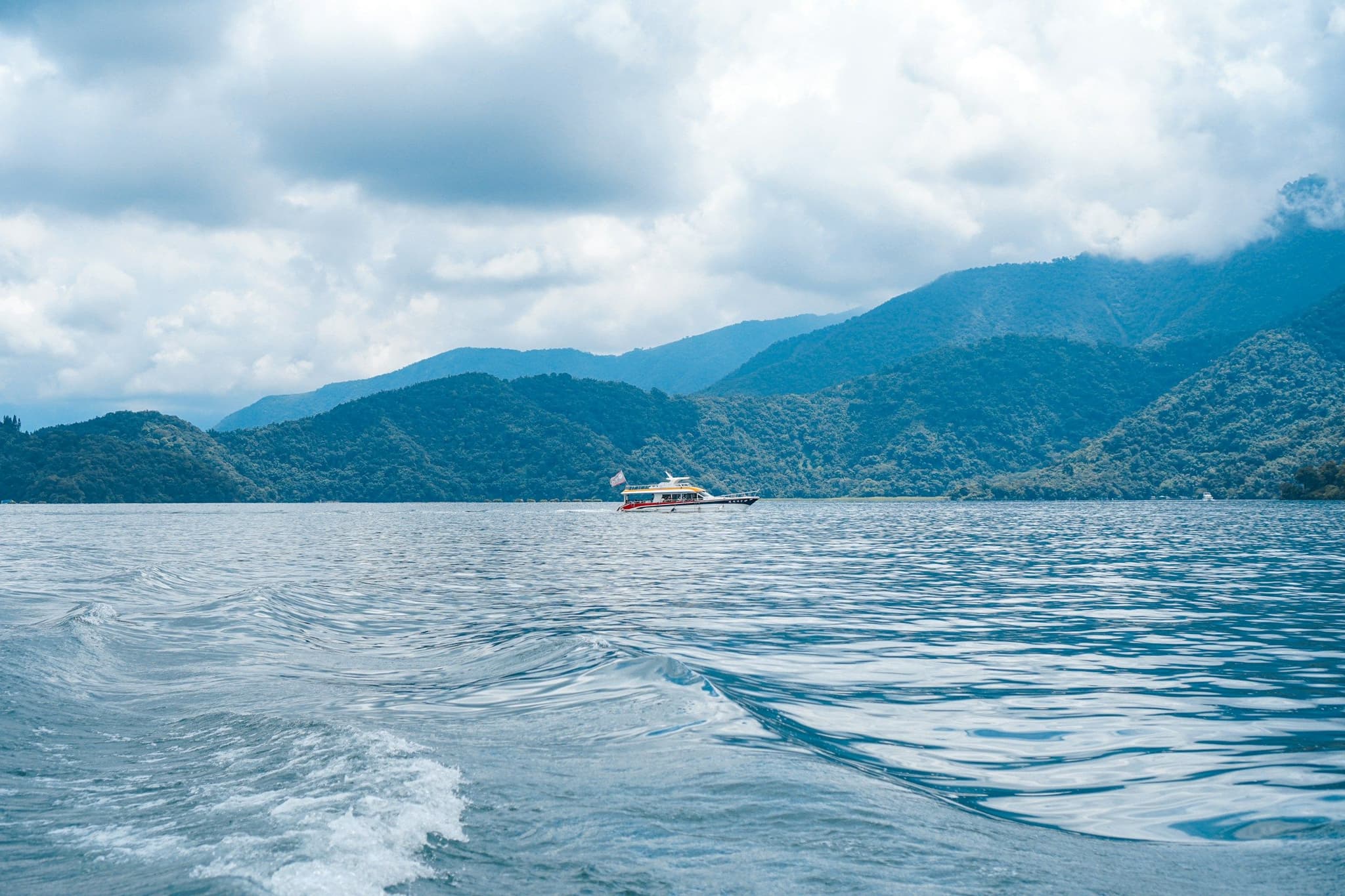 A ferry crossing Sun Moon Lake below green hills