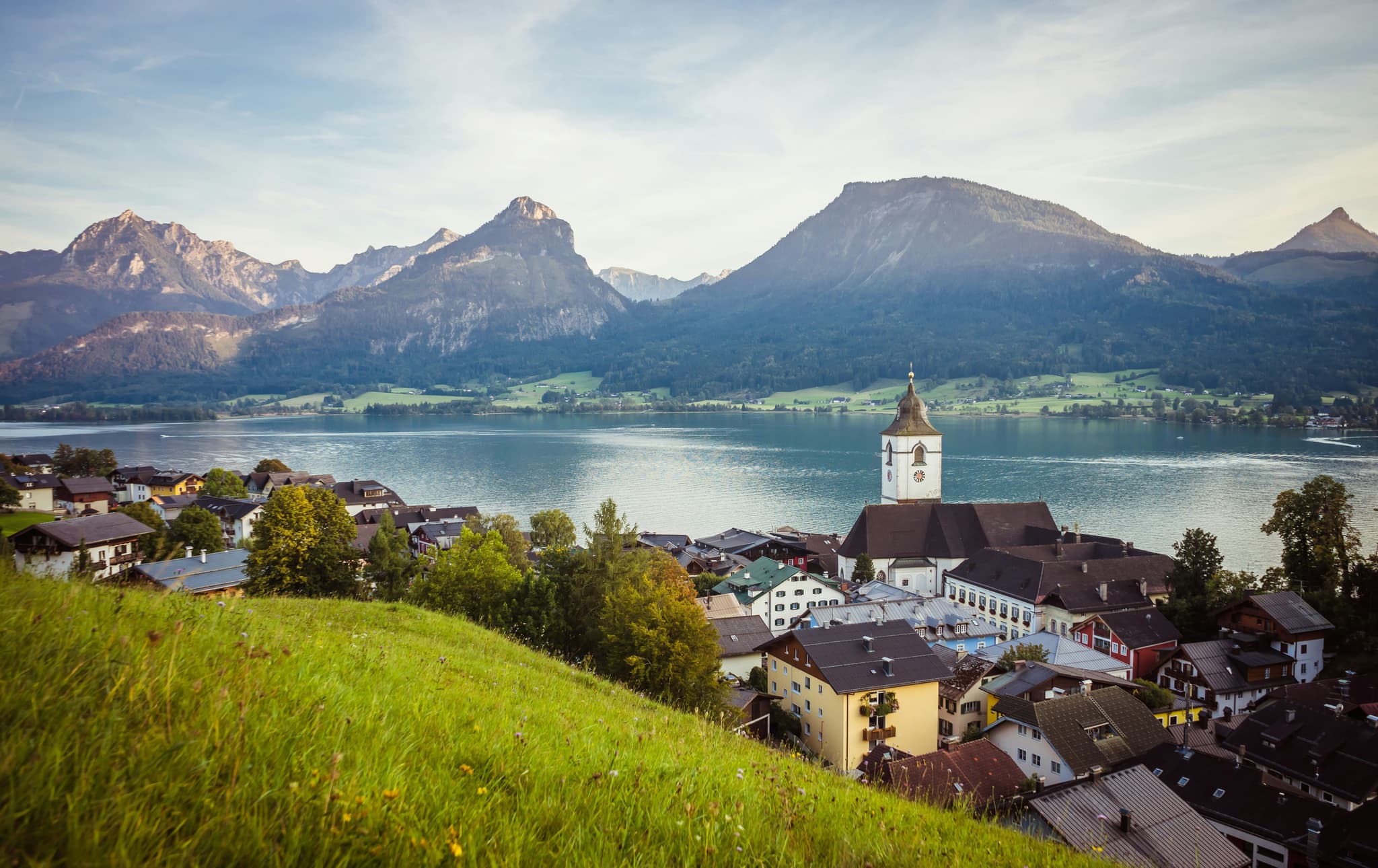Aerial view of Salzkammergut lake and surrounding mountains and village with church.