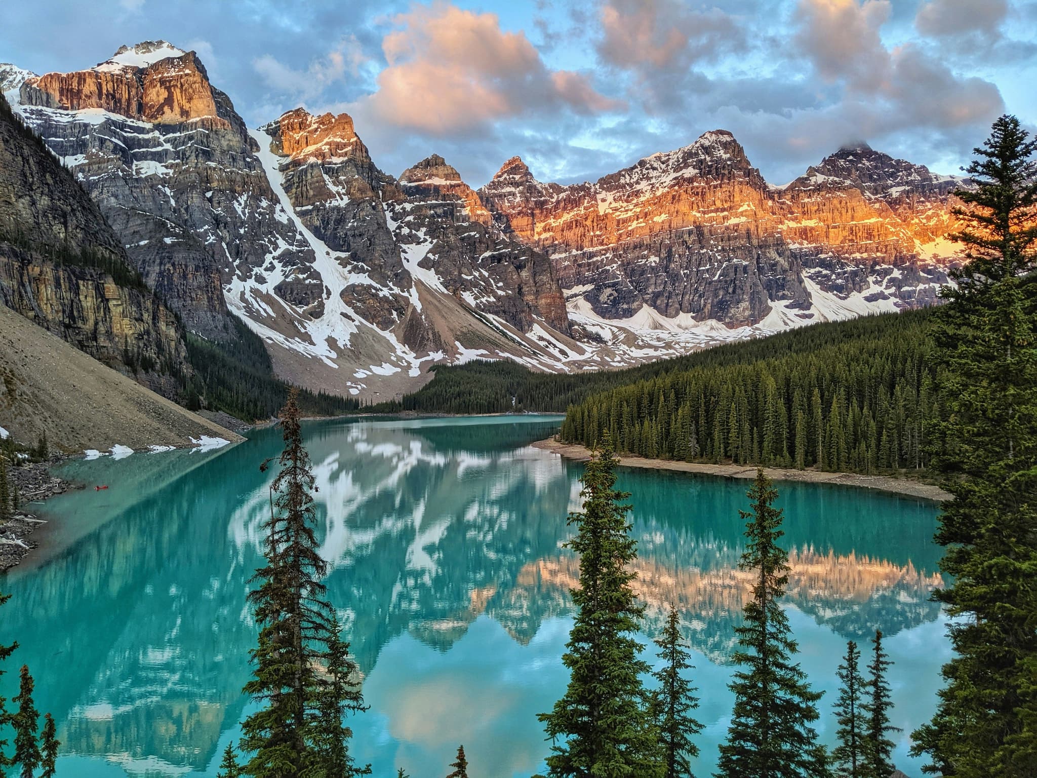 Turqoise water surrounded by pine rees and snow rocky mountains at Moraine Lake