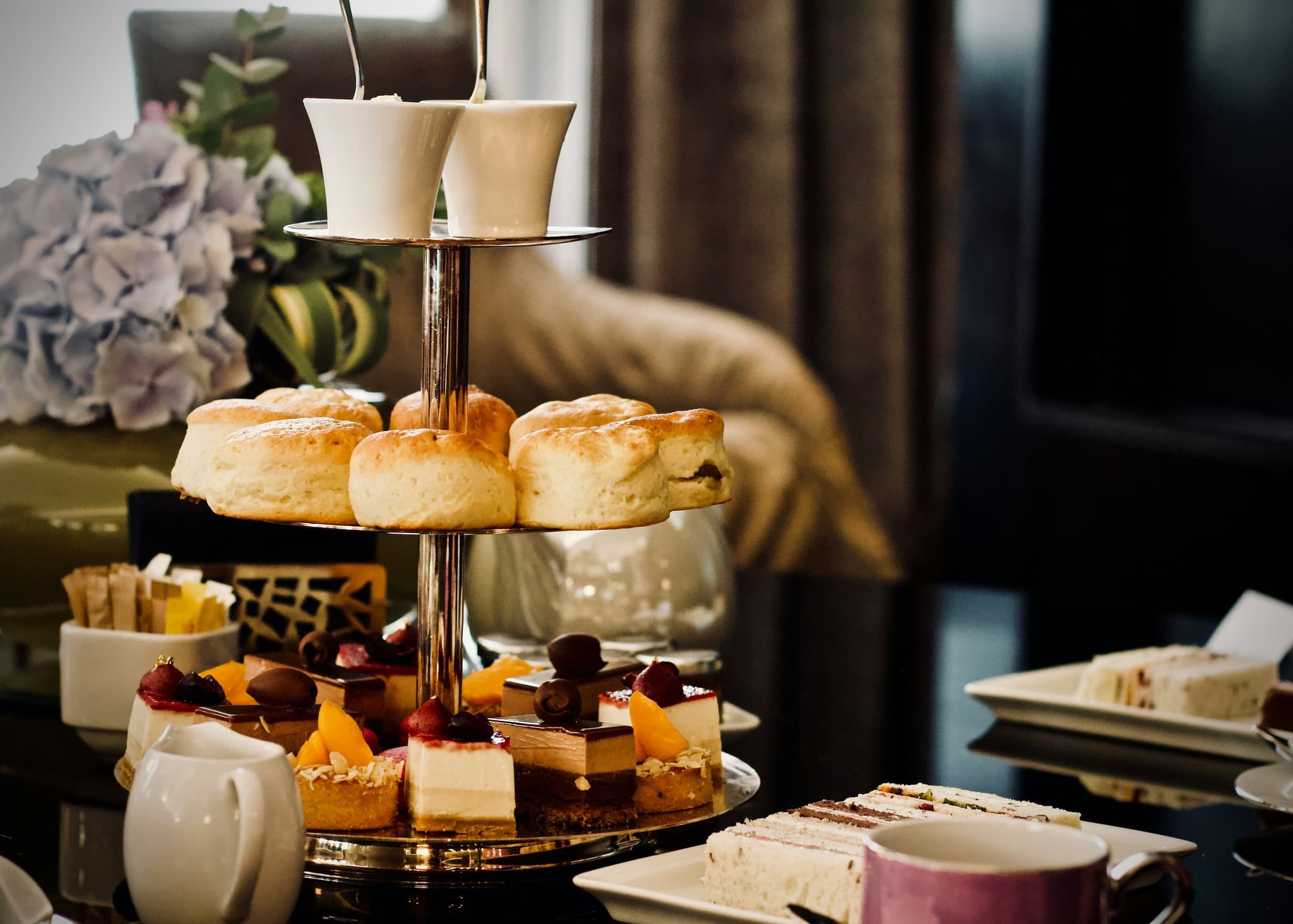 Afternoon high tea with a tray with scones, sweets on a table.