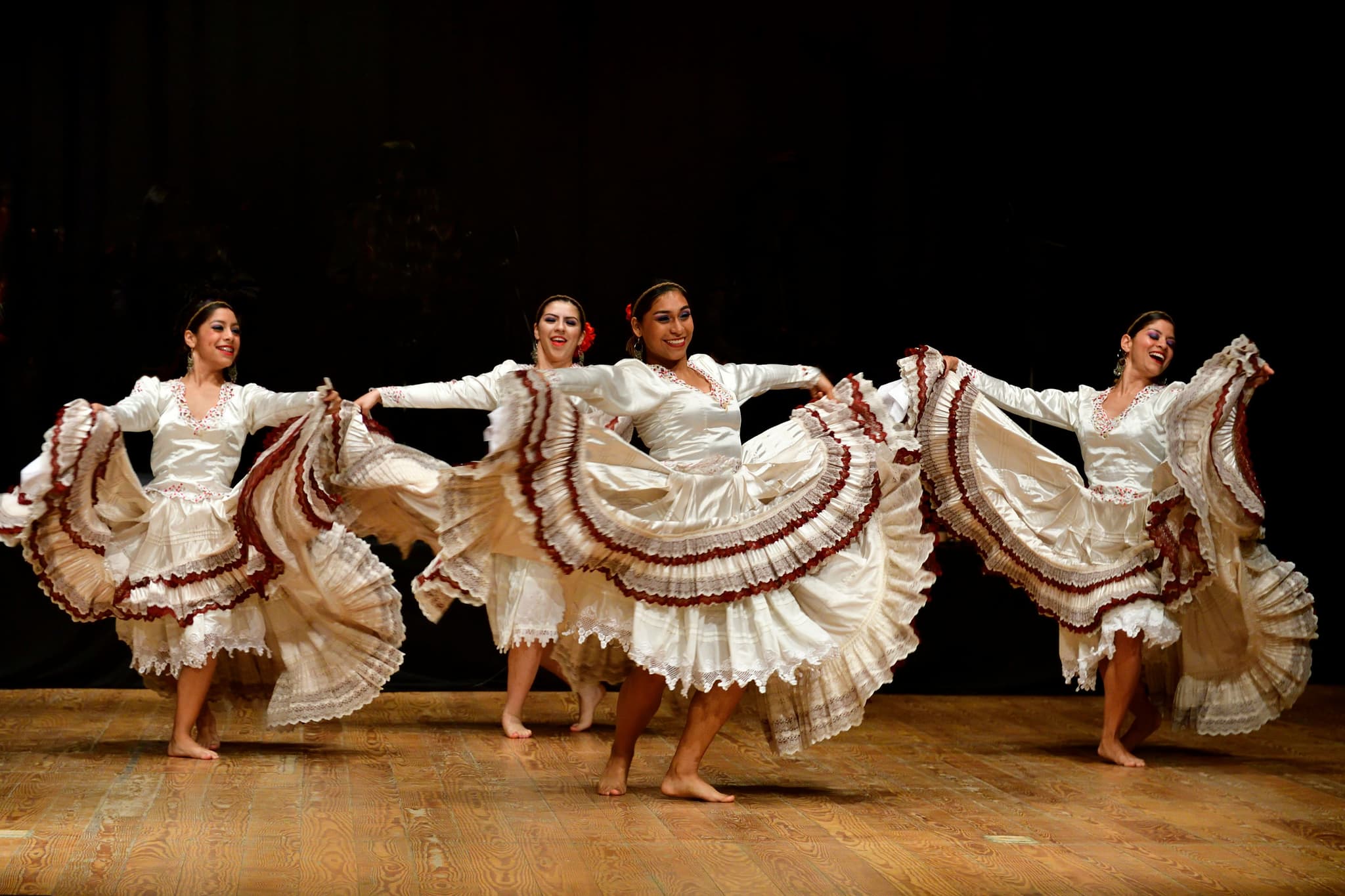 5 women dancing the flamenco in wide white dresses
